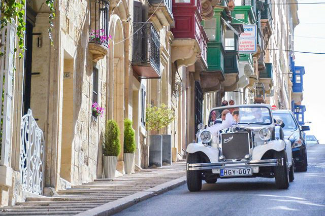 Vintage open-top wedding car in a Maltese street